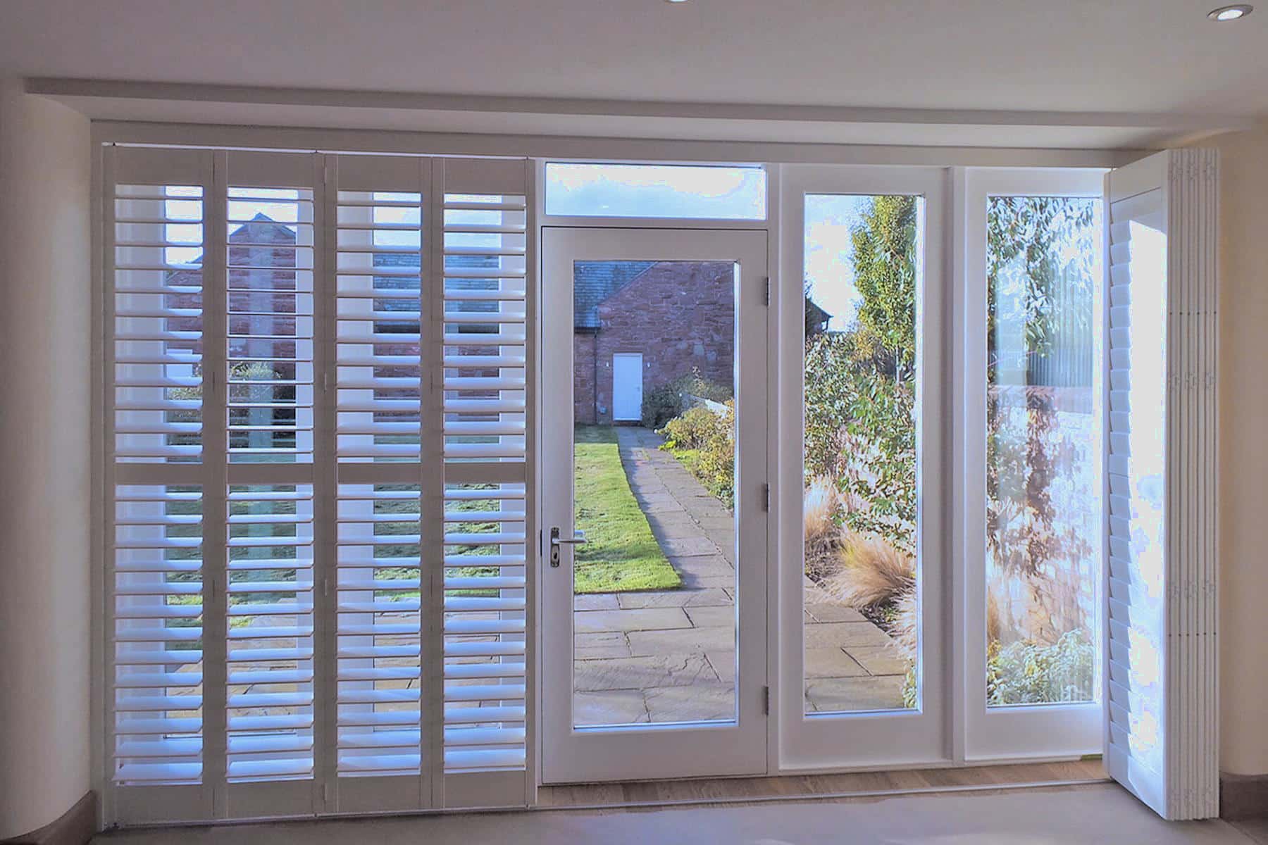 Bespoke fitted window shutters in Higham installed by London Essex Shutters and Blinds, featuring white plantation shutters alongside a garden-view glass door