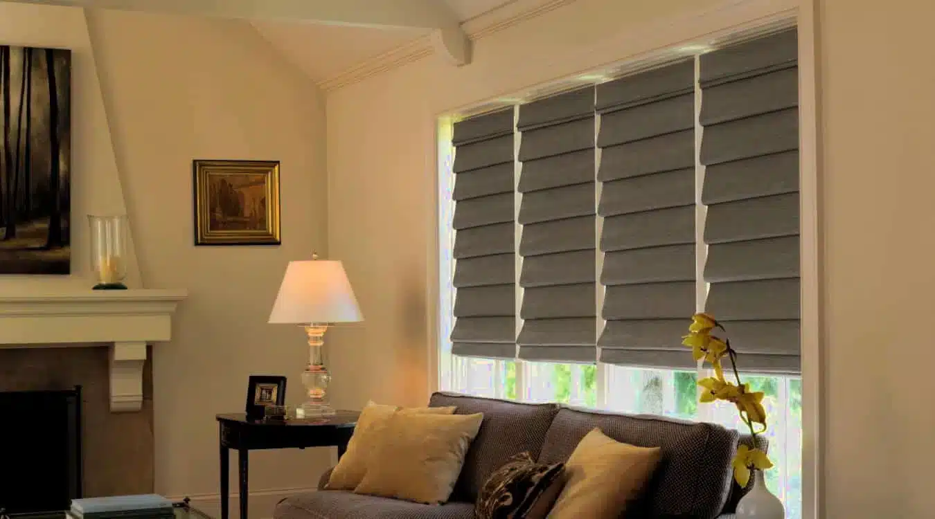 Professional shutter installation in East Horndon - stylish gray roman blinds installed in a modern living room with neutral decor
